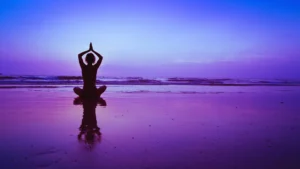 A person is sitting in the sand on the beach