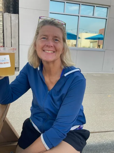 A woman sitting on the ground holding a cup.